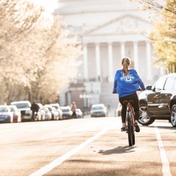 student wearing a Marquette shirt biking in DC