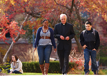Jesuit with students on campus